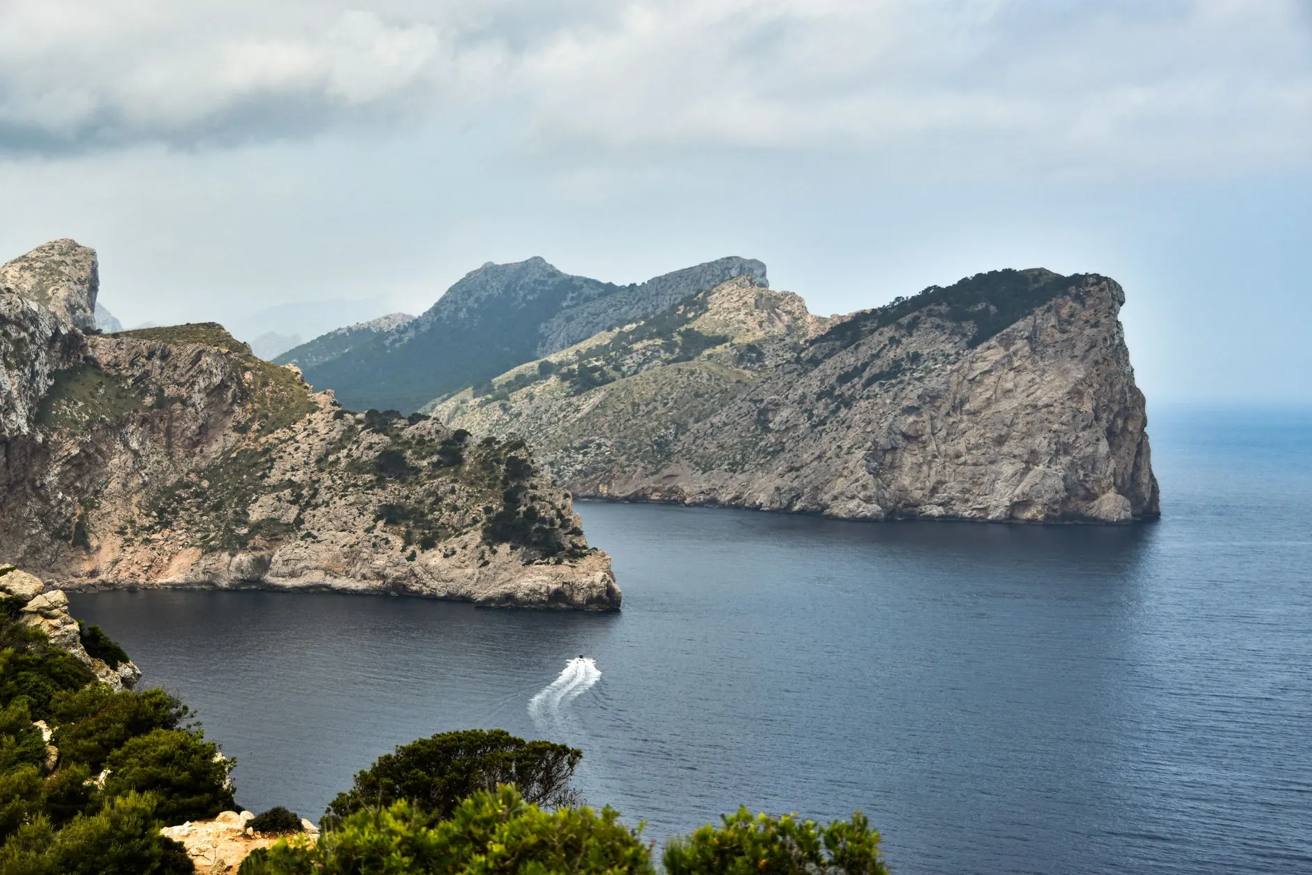 Dramatic cliffs and a serene ocean captured at Mallorca with a passing speedboat.